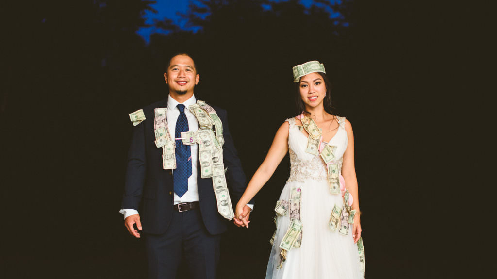 asian bride and groom covered in money from their money dance